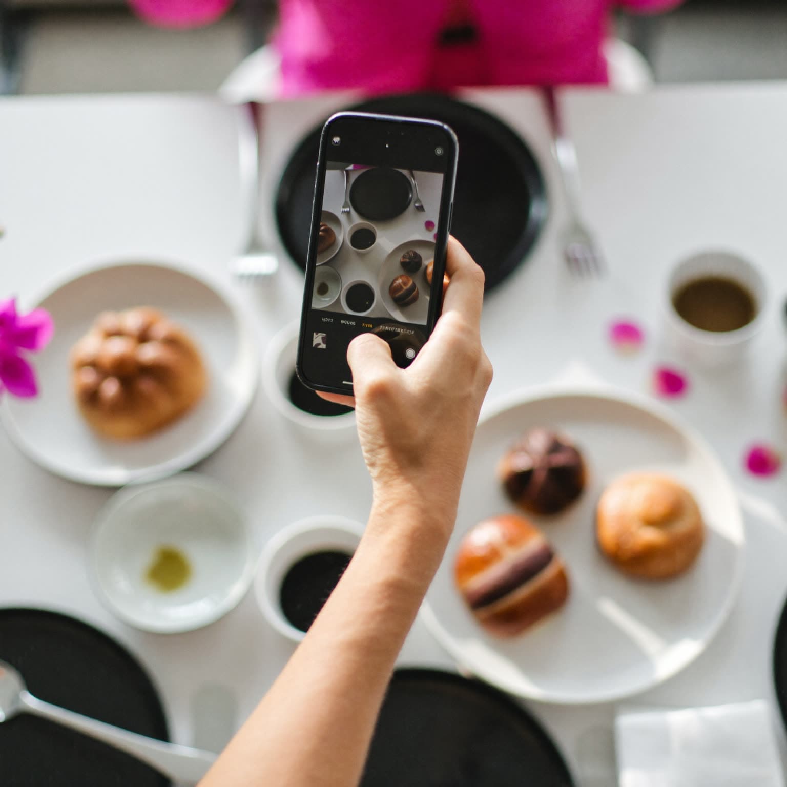Brunch-Tisch von oben, eine Hand hält das Smartphone über das Essen