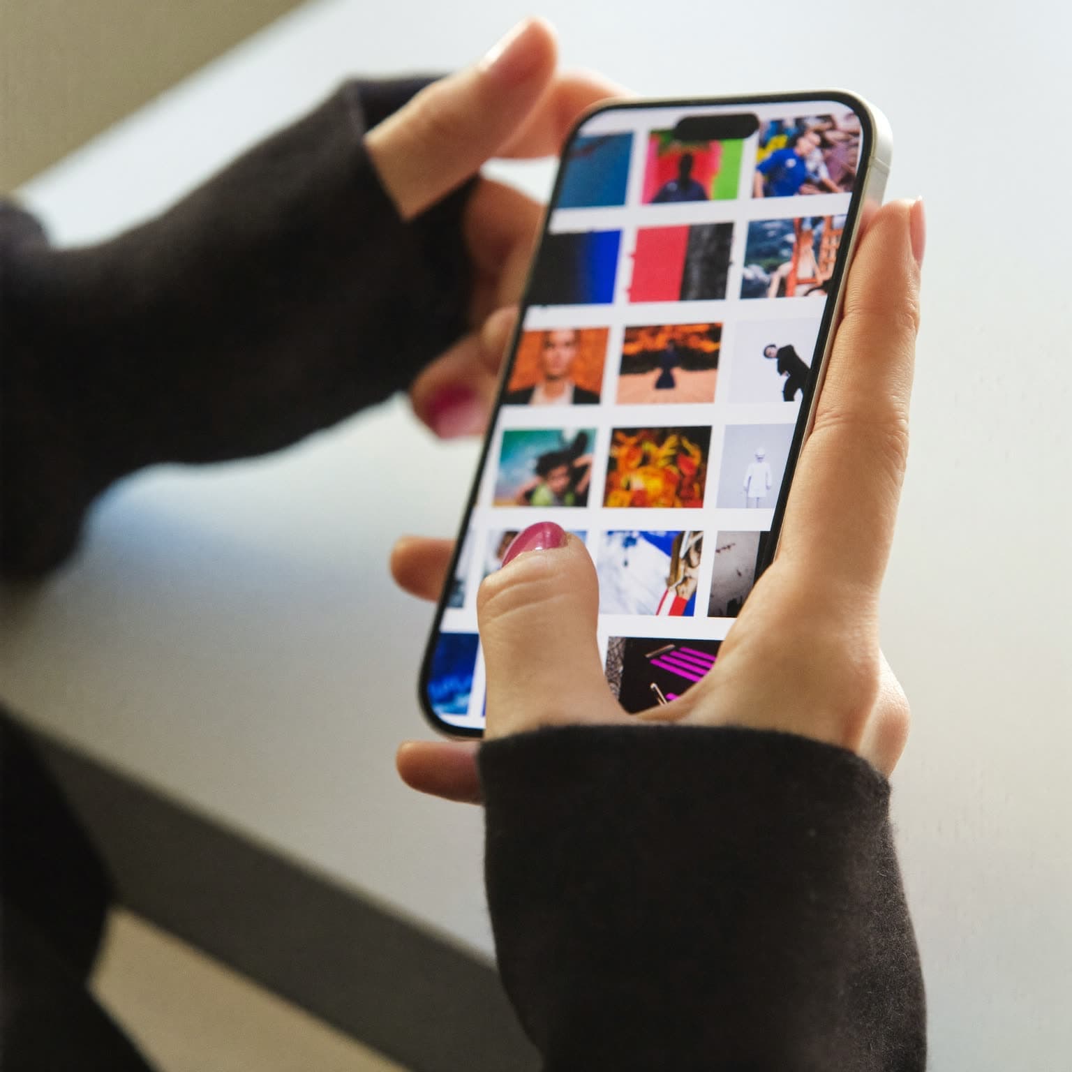 Hand hält ein Smartphone mit einem bunten Feed