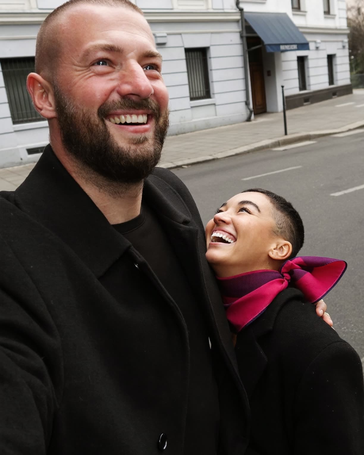 Zwei Freunde lachen auf einer Berliner Straße beim Dreh eines Kurzvideos