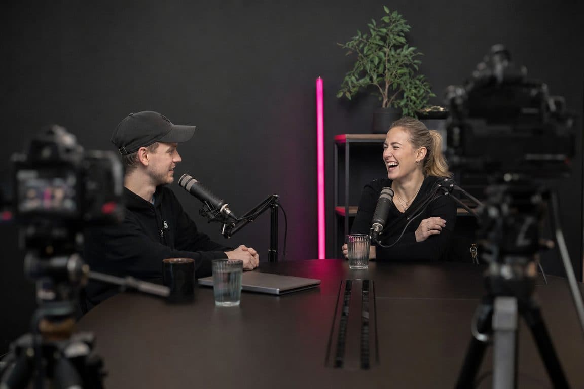 Videopodcast im Studio: zwei Gastgeber an Mikrofonen, davor zwei Kameras auf Stativen