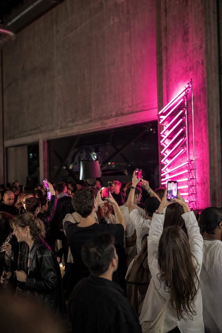 Gäste filmen bei einem Pop-up-Event eine pinke Neon-Installation mit ihren Smartphones