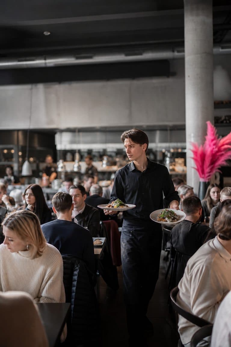 Kellner trägt Teller durch ein volles Restaurant
