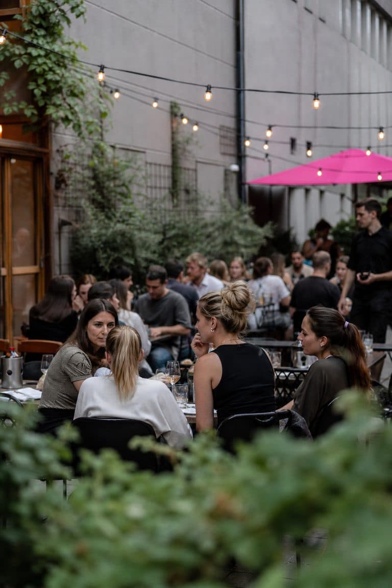 Restaurantterrasse in Berlin mit Lichterkette und Gästen