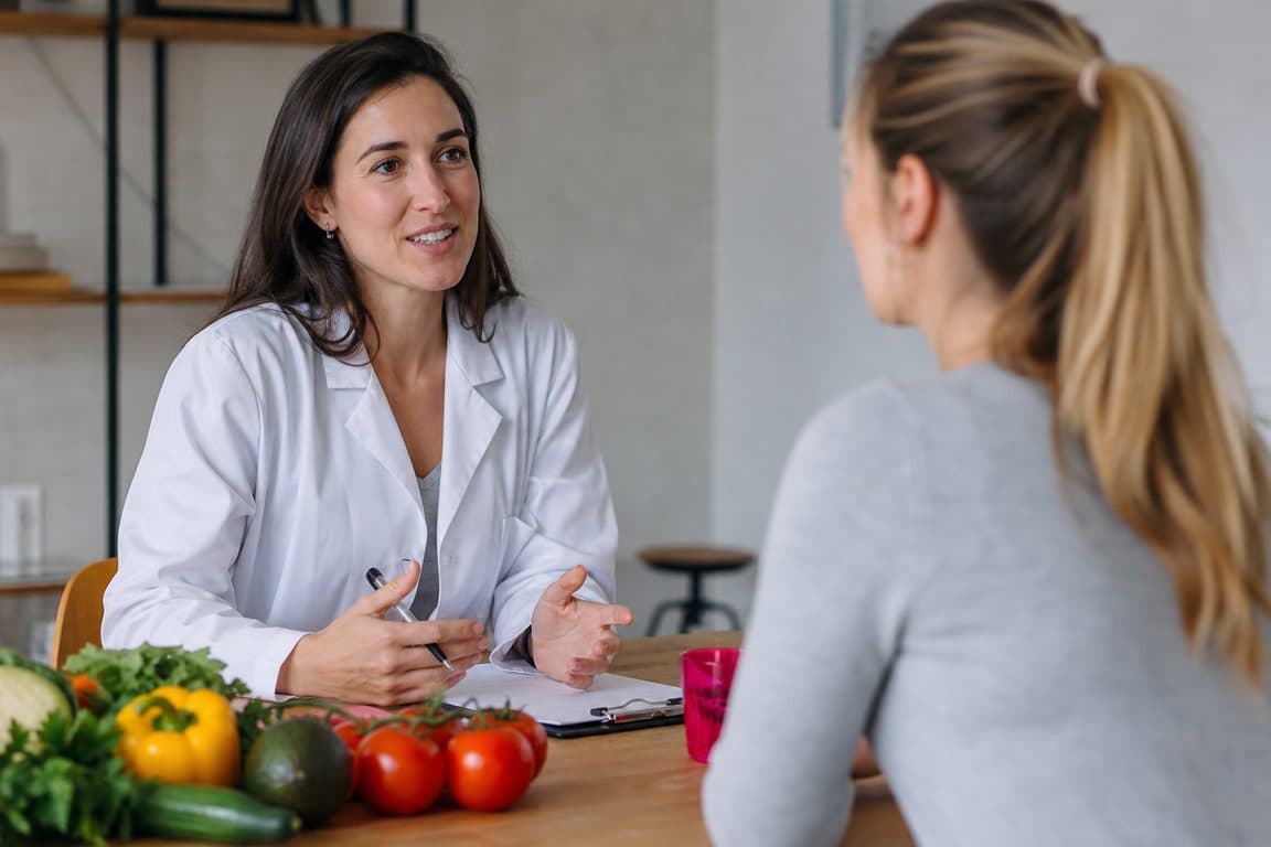 Ernährungsberaterin im Gespräch mit einer Klientin, frisches Gemüse auf dem Tisch