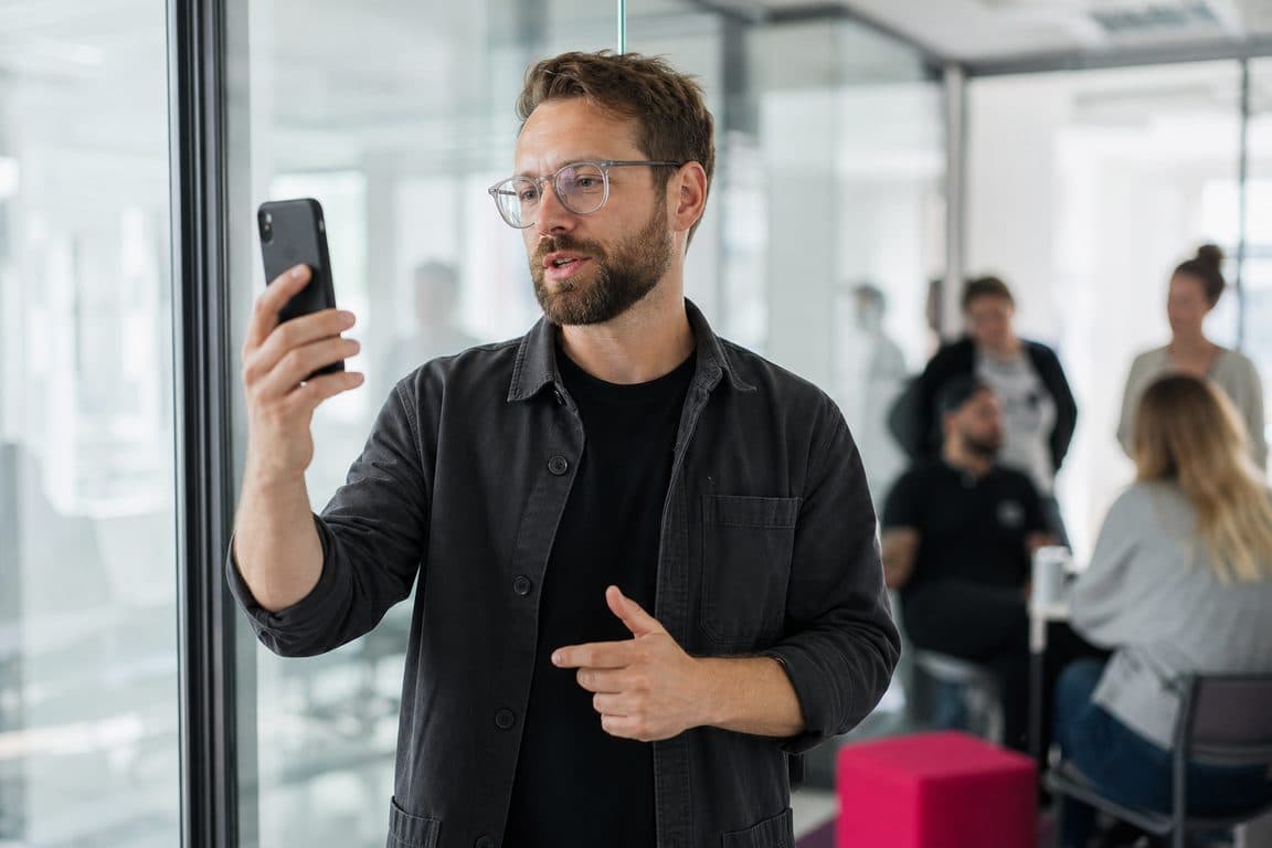 Managerin nimmt im Glasbüro ein kurzes Statement mit dem Handy auf