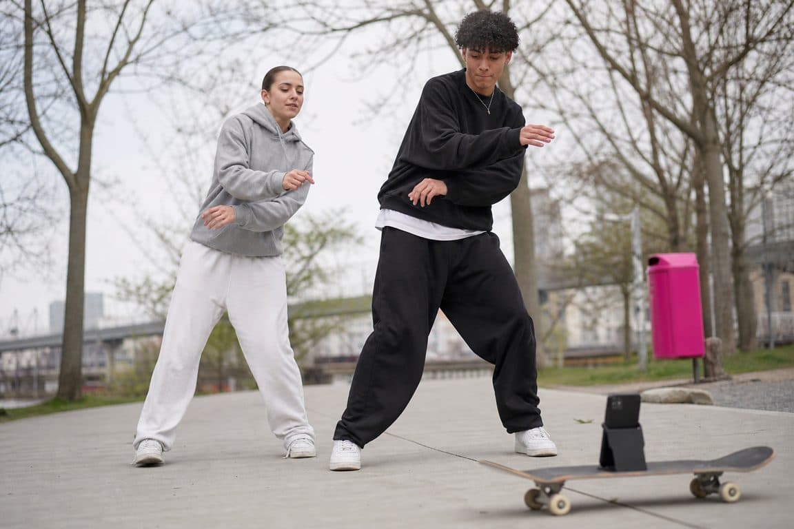 Zwei Jugendliche drehen im Park einen kurzen Tanzclip vor dem Handy