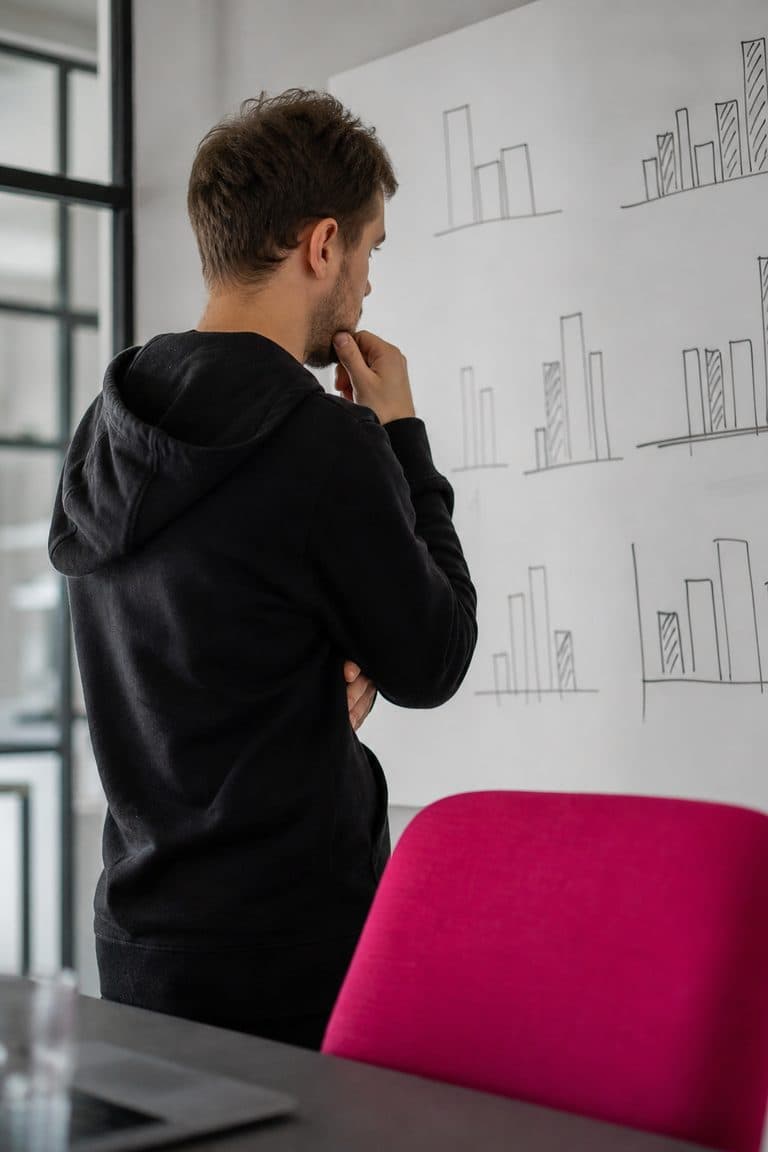 Analyst denkt vor einem Whiteboard mit skizzierten Balken nach