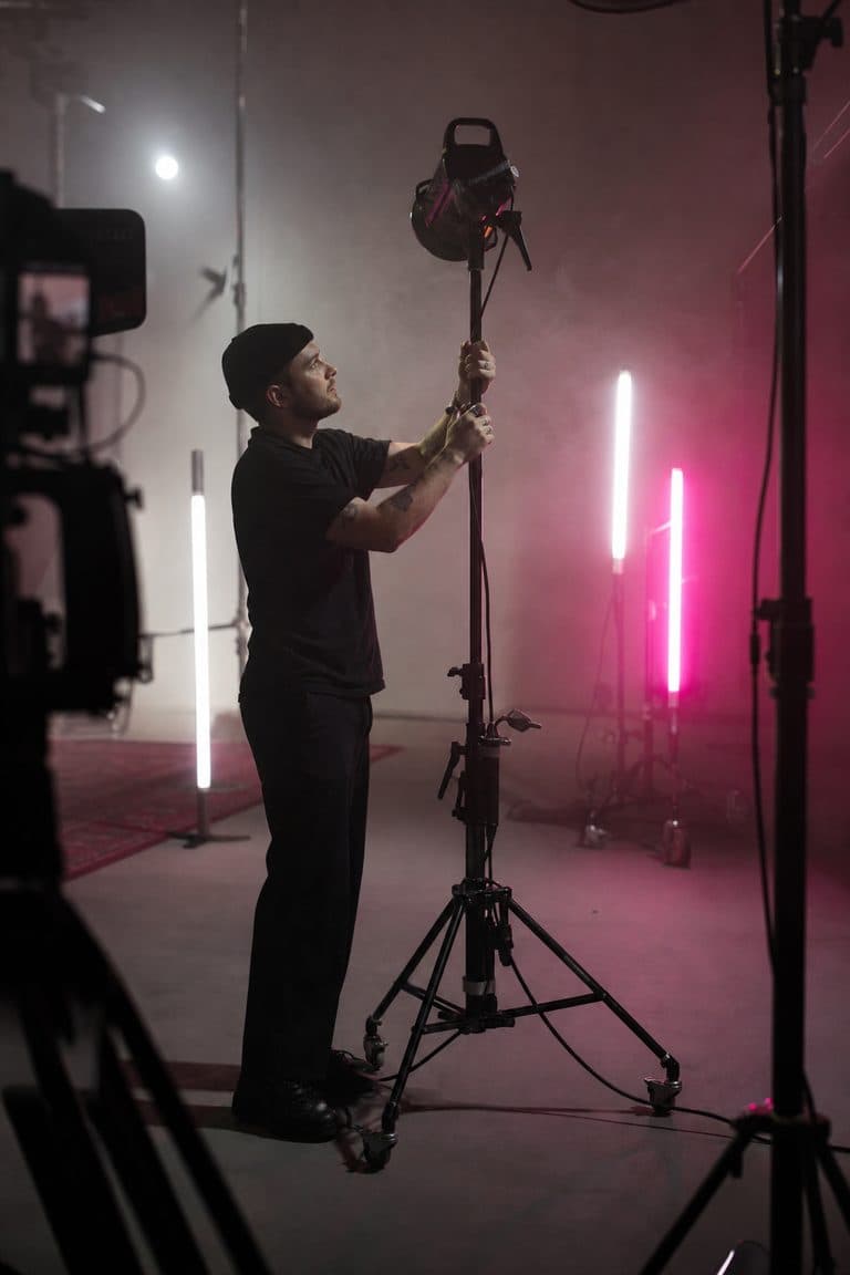 Gaffer richtet farbige LED-Röhren in einem kleinen Filmstudio ein