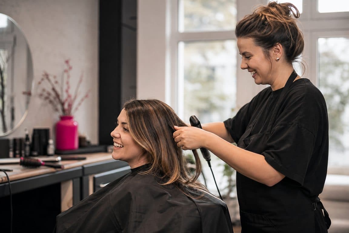 Friseurin im Gespräch mit einer Kundin in ihrem Salon