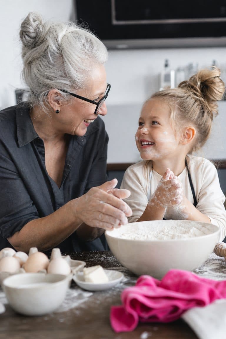 Großmutter und Enkelin backen zusammen am Küchentisch