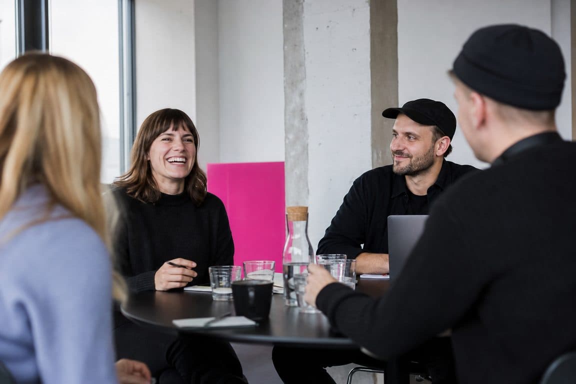 Eine Kundin lacht entspannt im Gespräch mit dem Agenturteam