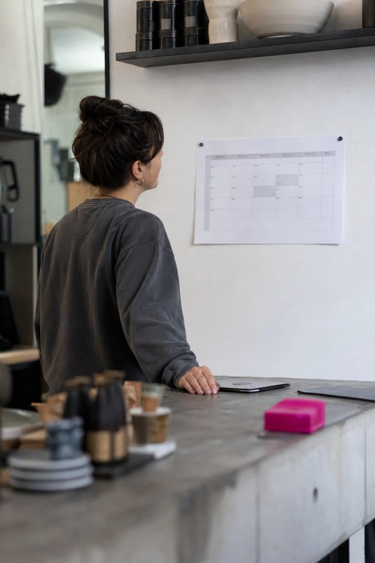 Ladeninhaber schaut auf einen Wochenplan hinter der Theke