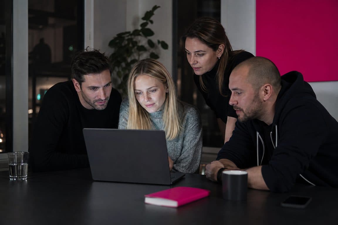 Agenturteam schaut nach Feierabend konzentriert auf einen Laptop