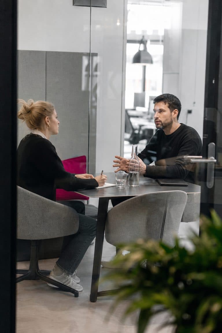 Zwei Kollegen besprechen sich ernst in einem Glasraum