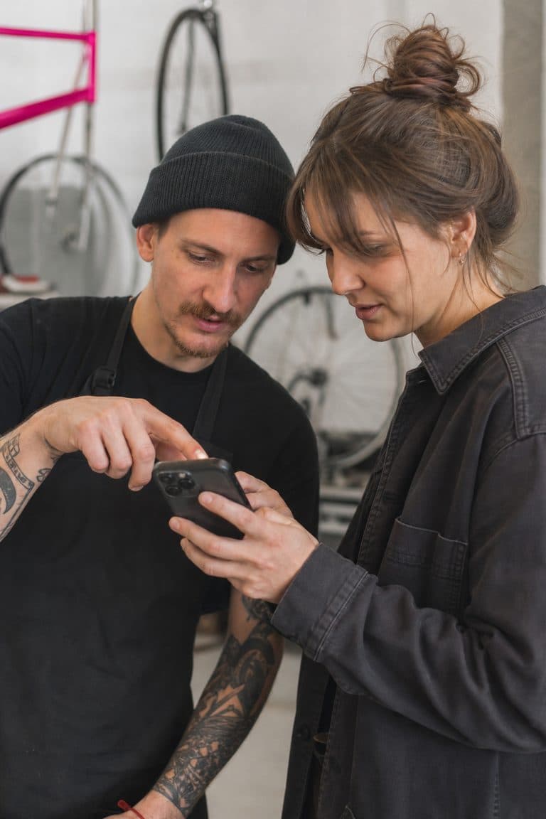 Fahrradmechaniker zeigt einer filmenden Kollegin eine Reparatur