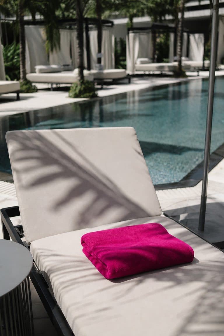 Sonnenliege mit pinkem Handtuch an einem Hotelpool