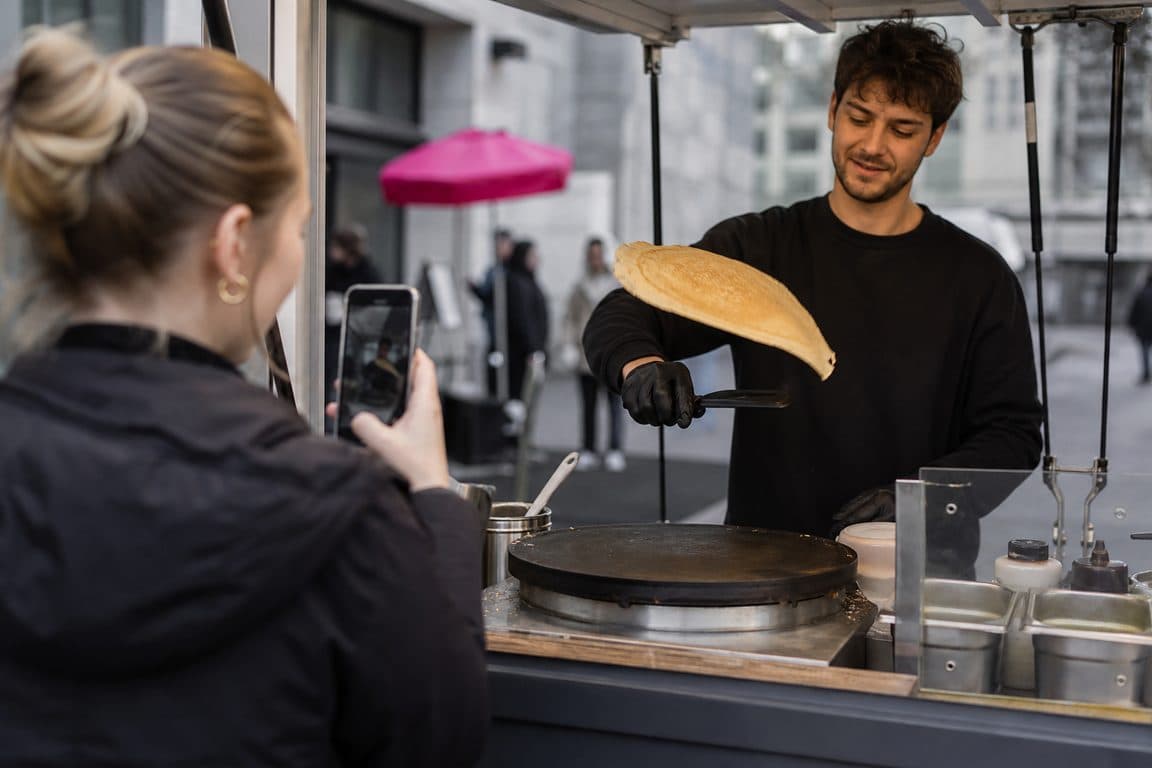 Straßenverkäufer wendet einen Crêpe, eine Kundin filmt mit dem Handy